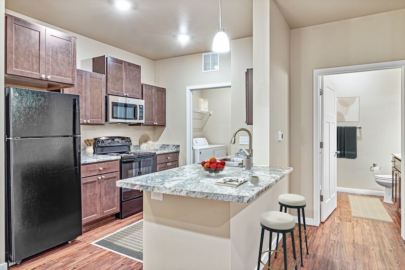 One-bedroom kitchen with island, stools and stainless microwave