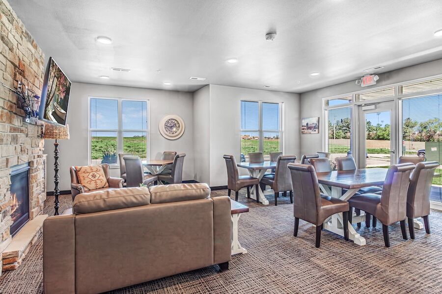 Community dining tables beside large windows, with a seating area