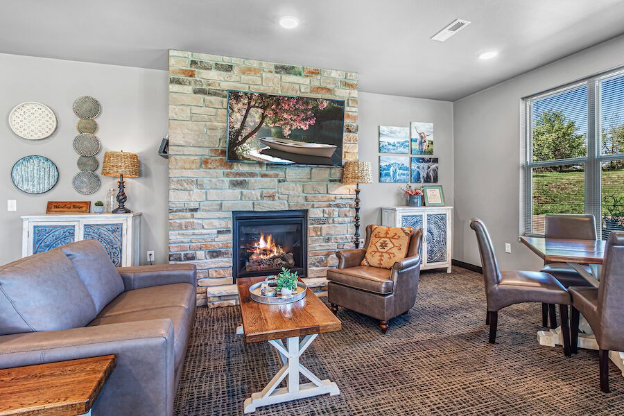 Community lounge with stone fireplace, sofas and dining tables