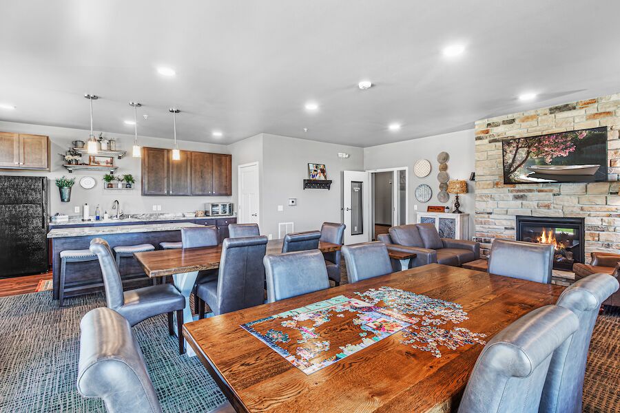Gathering room with a puzzle on the table, kitchen and fireplace beyond